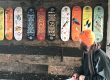 An artist sitting with his range of illustrated skateboards.